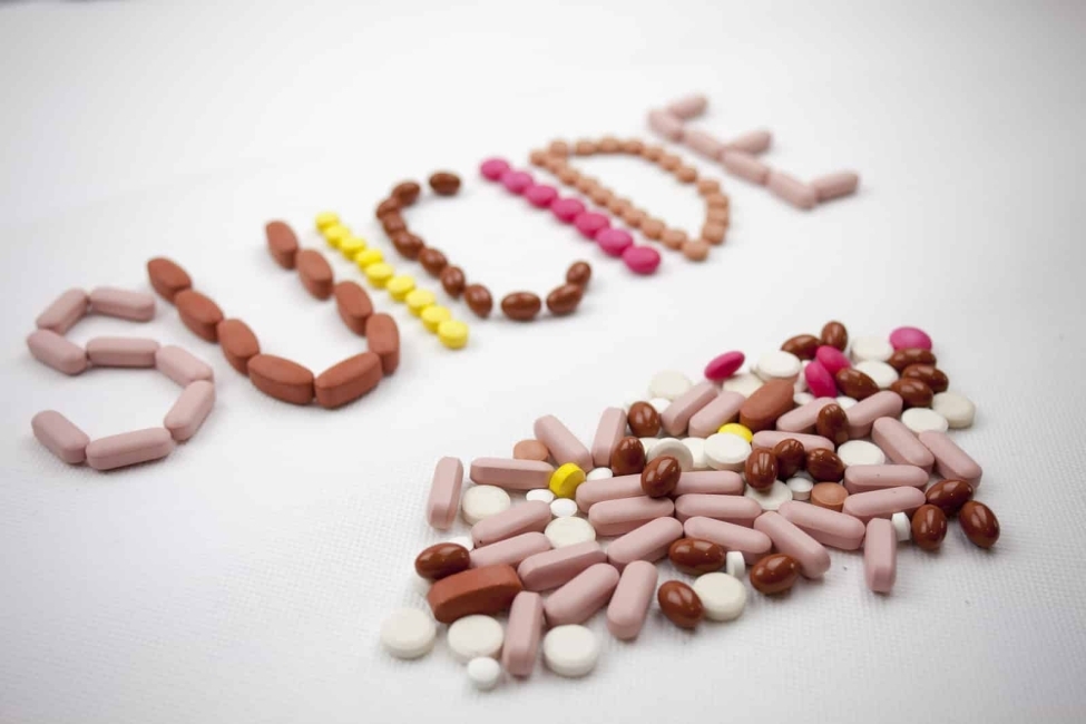 A suicide word writing on the white background on pills to illustrate the invisible patient article